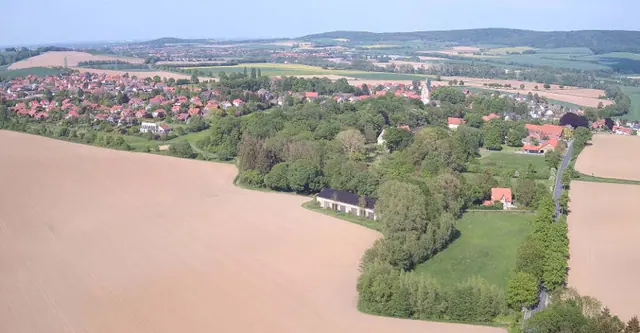 Luftbild: Felder, das bewaldete Tal des Riesbachs und dahinter das Dorf Apelern