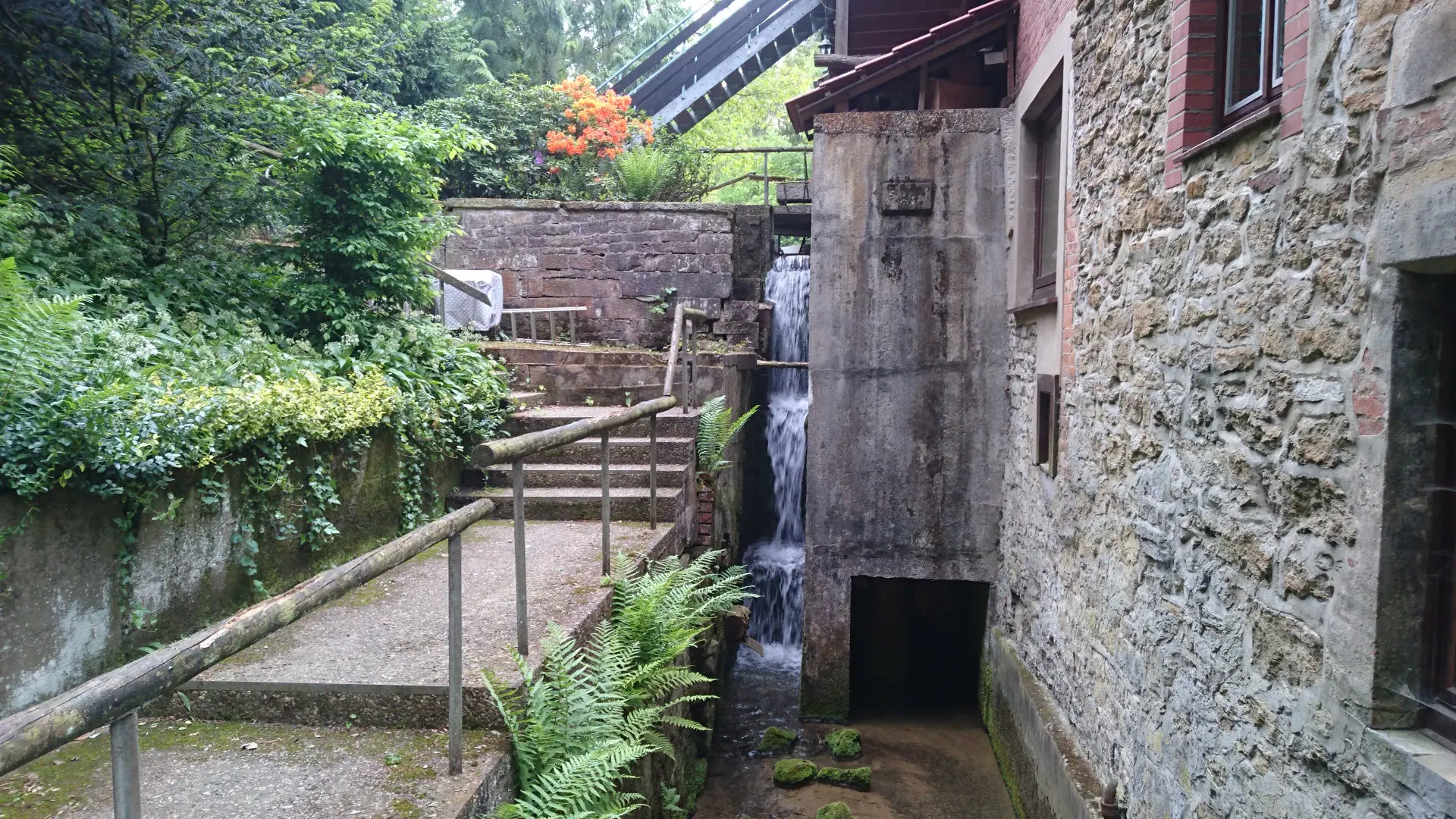 Concrete block housing the turbine at the mill wall, the waterfall beside it